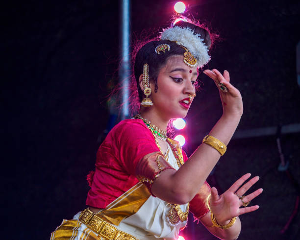 Outdoor image of young Asian/ Indian woman standing in park and pointing away on free space