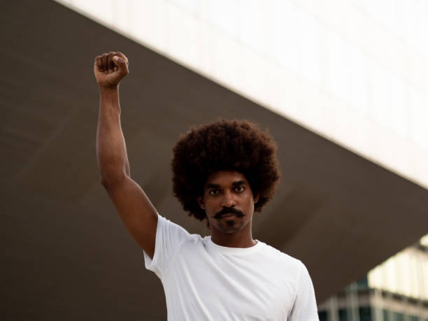 giovane afroamericano con i capelli afro con pugno alzato come simbolo antirazzista - anti racism foto e immagini stock