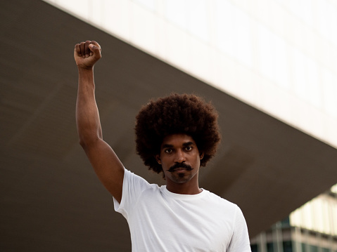 Young african american man with afro hair with fist raised as anti-racist symbol