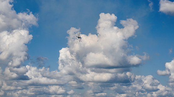 A small propeller airplane flying between white clouds in the sky