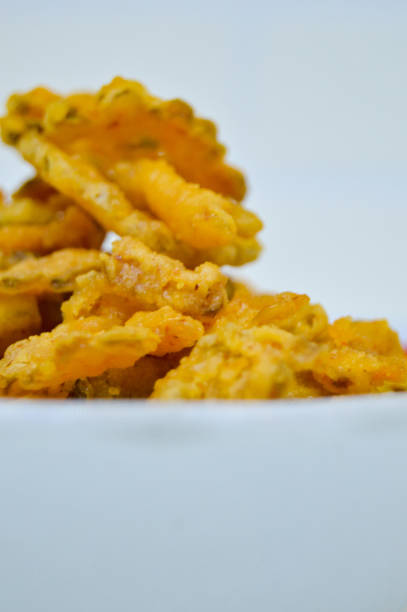 Savory and delicious bitter melon chips in a bowl on a white background.