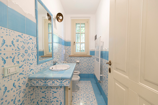 Old fashioned bathroom with textured blue tiled walls and white fixtures.