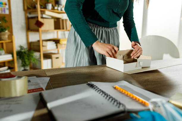 istock Young female entrepreneur assembling a cardboard box at her desk 1417278843