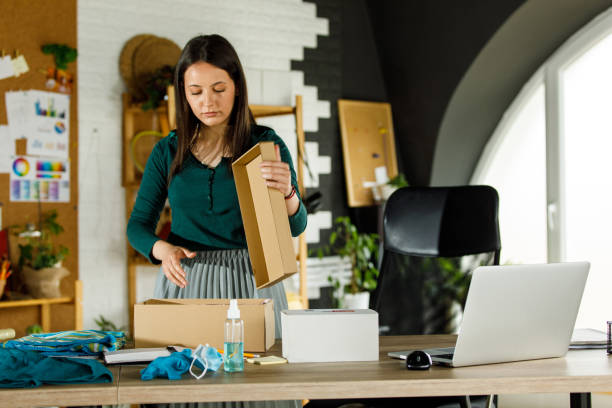 istock Young woman opening a cardboard box to pack customer's order 1417278846