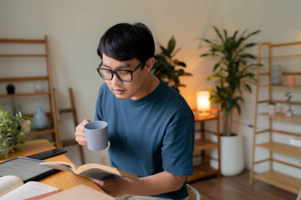 istock Asian man reads an educational book at his home. 1417284551