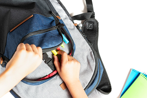 Close up of a child's hands looking for his pencils and markers in his school bag. High quality photo