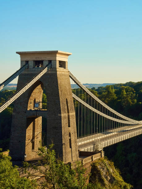 The Bridge’s Beginning The famous Clifton Suspension Bridge at Bristol in dramatic side-lighting from a setting summer sun. clifton stock pictures, royalty-free photos & images
