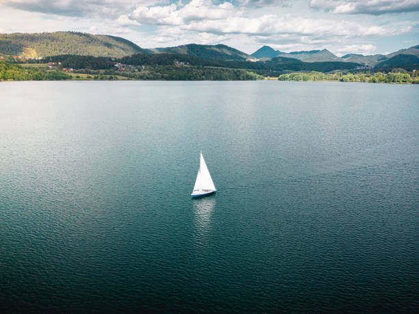 A dreamlike aerial drone shot of a beautiful sailing boat on lake with sparkling waters. The riverscape looks great and gorgeous