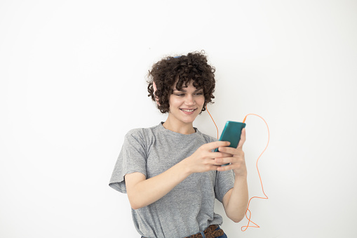 Studio portrait of a beautiful, young woman enjoying music from her smartphone