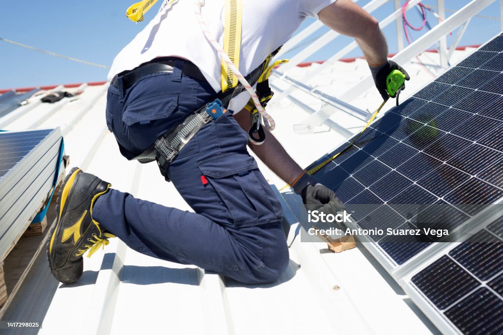 A worker measures solar panels with a meter to install them on the rooftop Solar Panel Stock Photo