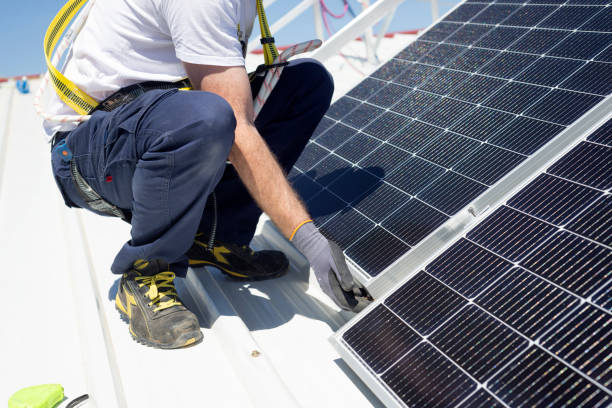 A worker installs solar panels on a rooftop. Renewable energy concept stock photo
