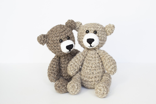 Crocheted gray and brown bears on a white background. Crocheted toy. Crocheted bear