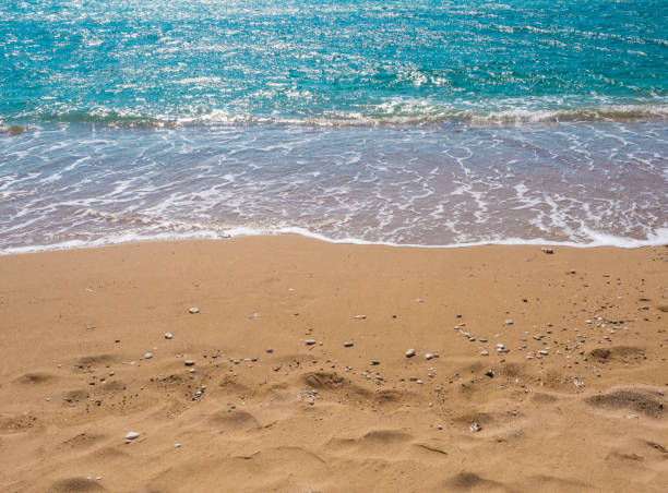 turkusowo-niebieska krawędź powierzchni wody morskiej na piaszczystej plaży z kamykami, sumer wakacje naturalne tło - waters edge wave beach soap sud zdjęcia i obrazy z banku zdjęć