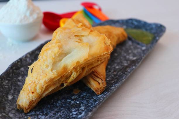 istock Puff pastry triangles filled with Vegetables like carrots, potatoes, peas and beans with some spices on wooden table 1417300657