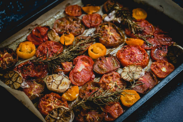 Metalowa taca z pieczonym czosnkiem i ziołami o różnym kolorze i rodzajach pomidorów – zdjęcie