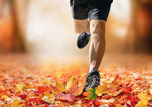 Man jogging in autumn park with fallen leaves