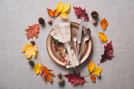 Thanksgiving autumn table setting with cutlery and arrangement of colorful fall leaves