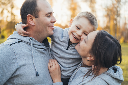 Autumn portrait with parents carrying children on shoulders. Good family relations concept.