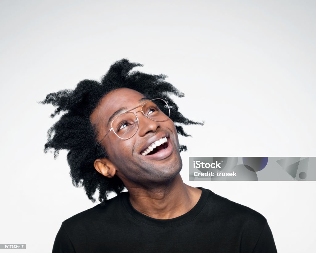 Headshot of excited man in black outfit Handsome afro american young man wearing black t-shirt, looking up and smiling. Studio shot on white background. White Background Stock Photo