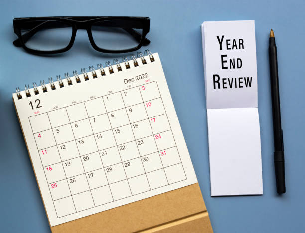 istock December 2022 desk calendar with Year End Review text written on notepad on blue background. Directly above. Flat lay. Copy space. 1417312741
