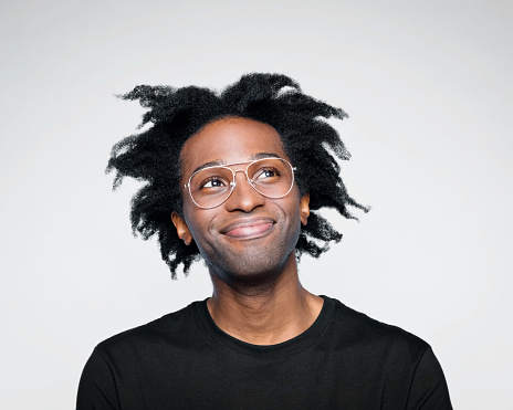 Happy afro american young man wearing black t-shirt, looking up and smiling. Studio shot on white background.