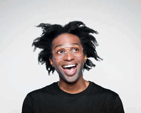 Excited afro american young man wearing black t-shirt, looking away with mouth open. Studio shot on white background.