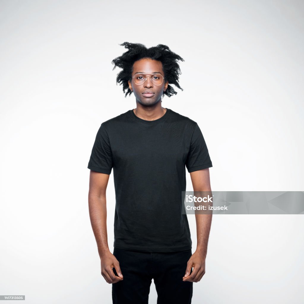 Portrait of handsome man in black outfit Confident afro american young man wearing black clothes, looking at camera. Studio shot on white background. T-Shirt Stock Photo