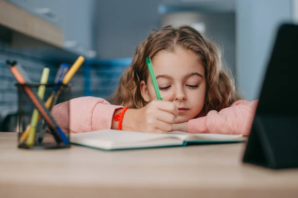 istock Cute girl learning online with video call from tablet at home, making notes. Internet technology. Online education. Education, learning, study. 1417314381