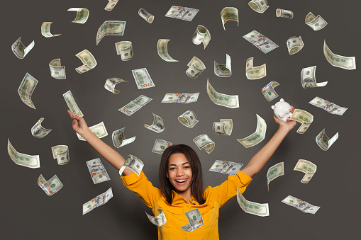 Portrait of a happy young woman throwing out money banknotes isolated over white background