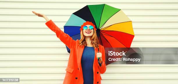 Autumn Portrait Of Happy Cheerful Smiling Young Woman With Colorful Umbrella Wearing Red Coat And Beret On White Background Stock Photo - Download Image Now