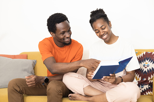 Portrait of a young African American couple enjoying at home together and reading a book