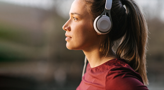 Side view portrait of a female athlete with ponytail listening to music while taking a break from jogging. Head shot with copy space