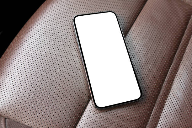 Smartphone in a car use for navigate or GPS. Driving a car with smartphone. Mobile phone with isolated white screen on brown perforated leather seat. Copy space. Empty space for text.