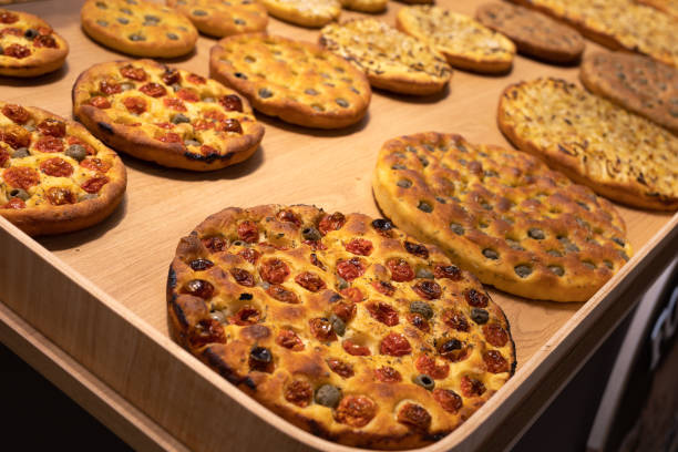 istock Round Flatbreads displayed in Bakery filled with Oregano, Tomatoes and Olives 1417321001