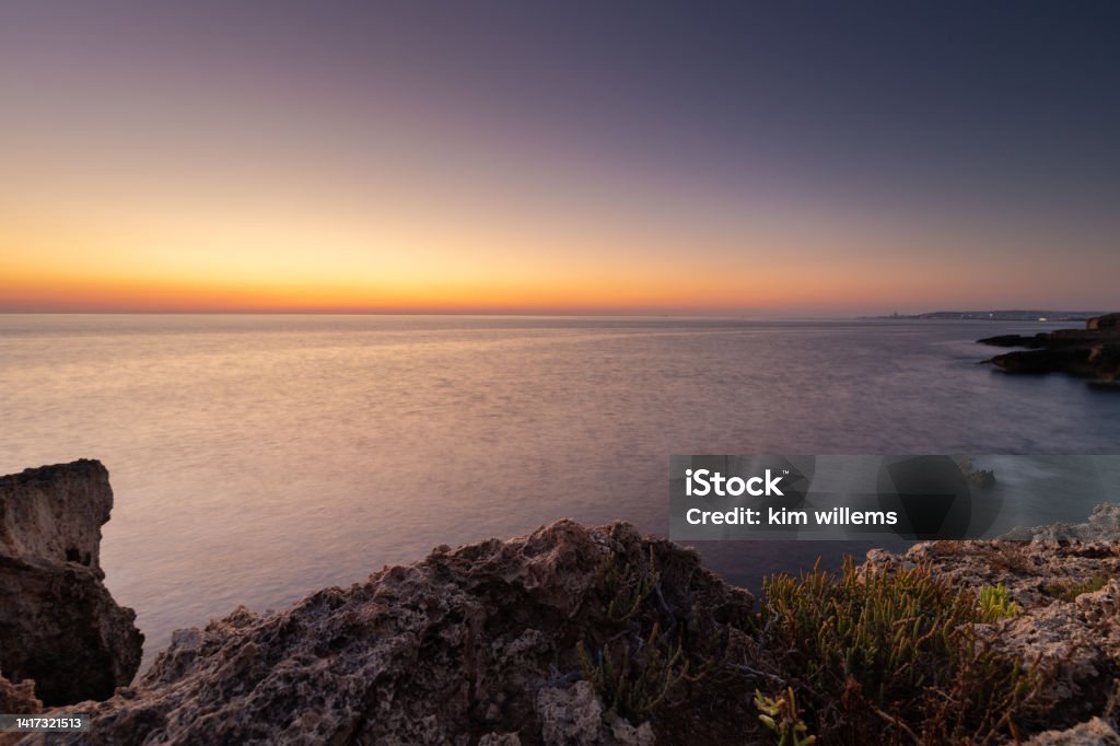 Amazing sunrise over the rising cliffs and rocks in Malta, with spectacular colors in the sky and reflections of the sun in het Mediterranean sea Amazing sunrise over the rising cliffs and rocks at Mellieha in the north west of Malta, with spectacular colors in the sky and reflections of the sun in het Mediterranean sea Mediterranean Sea Stock Photo