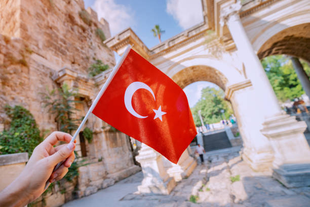 turkish flag in hand and famous gate or hadrian arch in antalya. travel landmarks and must-visit tourist and sightseeing sites in turkey - turkey tourist ephesus roman imagens e fotografias de stock