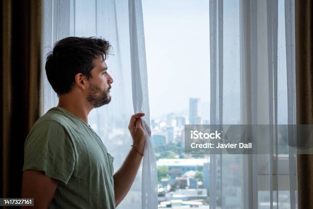 Young Man Looking Out The Window Of A Tall Building Stock Photo - Download Image Now