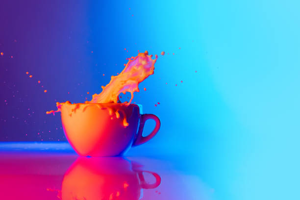 istock Huge milk splashes. Cup of coffee with milk standing on mirror surface over gradient blue white background in neon light. Concept of art, beauty, drinks 1417328481