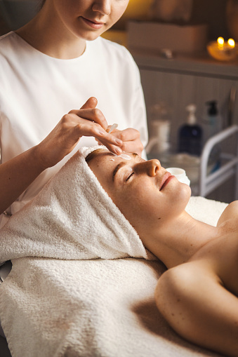 Esteticista masajea la cara de la mujer con loción crema en el salón de belleza. Belleza de la piel. Tratamiento médico. Tratamiento facial para niñas. Cuidado de la piel. photo