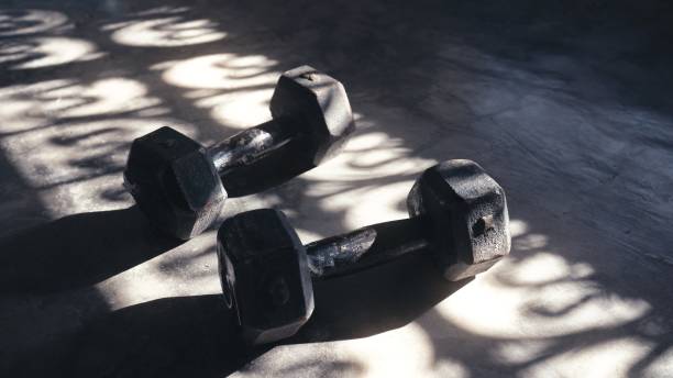 istock 5 kg dumbbells on the floor - shadows and sun rays 1417336563