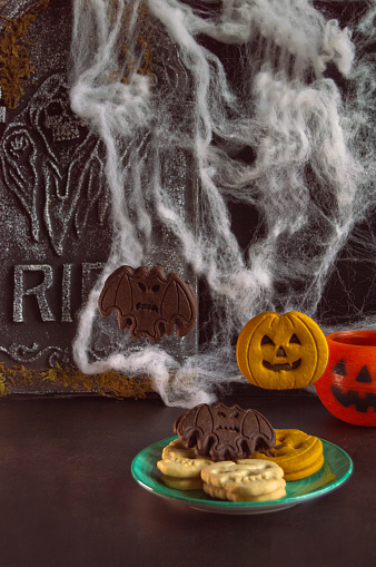 Delicious homemade cookies with halloween decorations on tombstone background and cobwebs