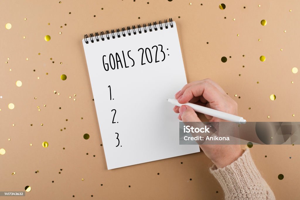 New Year goals 2023. Woman's hand writing in note pad goals list. Concept of new year planning New Year goals 2023. Woman's hand writing in note pad goals list. Concept of new year planning. Flat lay, top view Aspirations Stock Photo