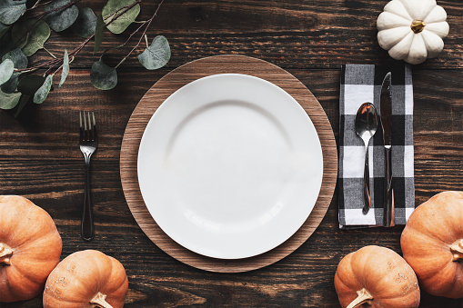 Place setting with plate, napkin, on a  decorated table shot from flat lay or top view position. Happy Thanksgiving Day spelled out with wood block letters.
