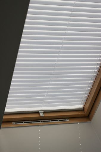 Pleated blinds on roof windows close up in the interior. Blinds for skylights. White color.