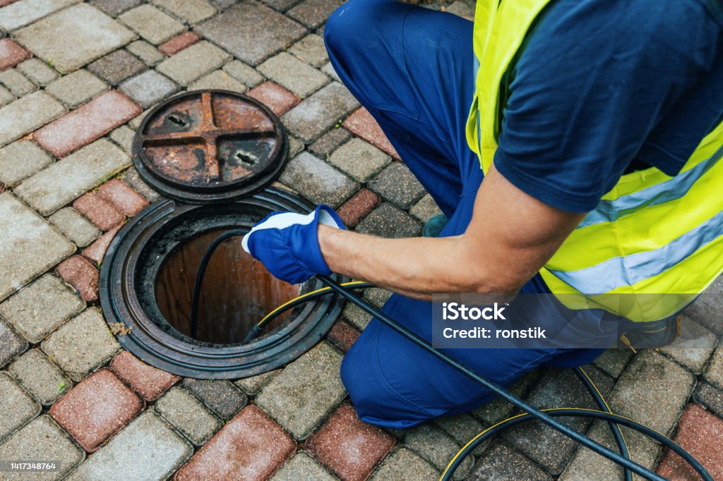 service worker cleaning blocked sewer line with hydro jetting Sewer Stock Photo