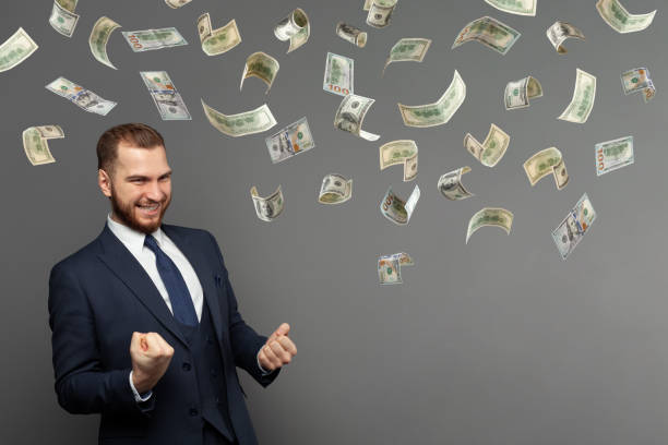 istock Joyful business man with hundred dollar bills on grey backdrop 1417351254