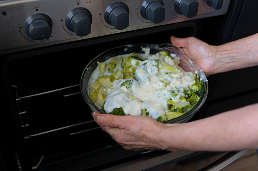 person baking a vegan broccoli stew in a modern oven