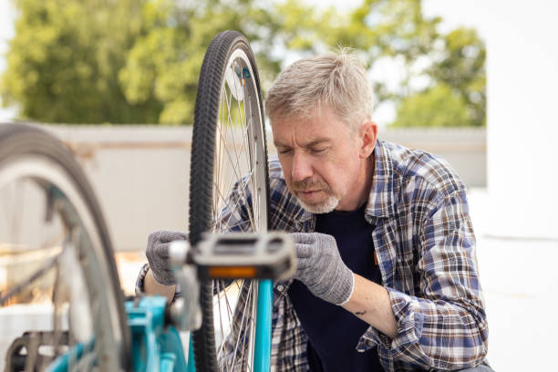 istock 50 year old man repairing a bicycle wheel 1417353132