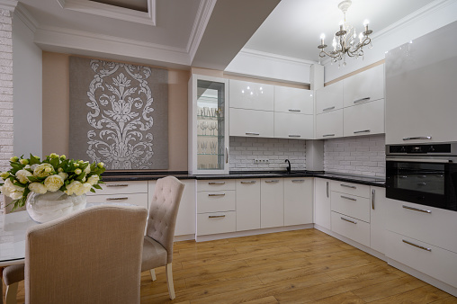 Luxury white modern kitchen with pink and white walls and laminated wooden flooring in studio apartment