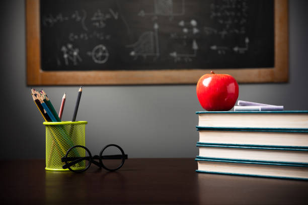 Close-Up Of Apple On Stacked Books Against Blackboard